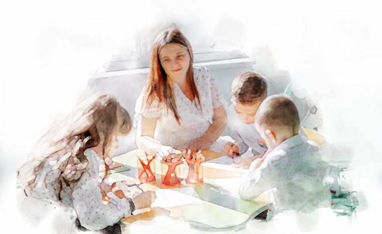 A woman sits at a table with three children