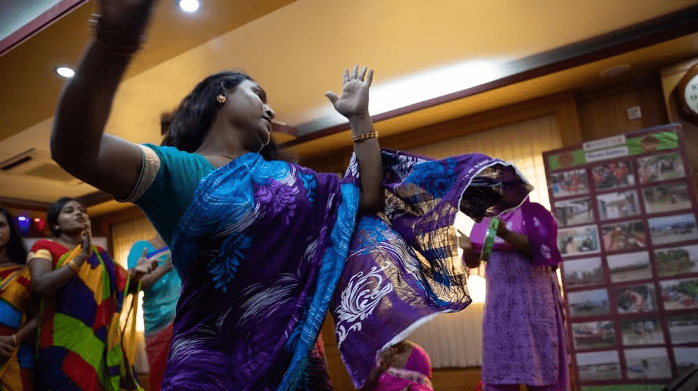 Bangladesh’s hijra group dressed in pink and purple clothing and sits and speaks among a group.